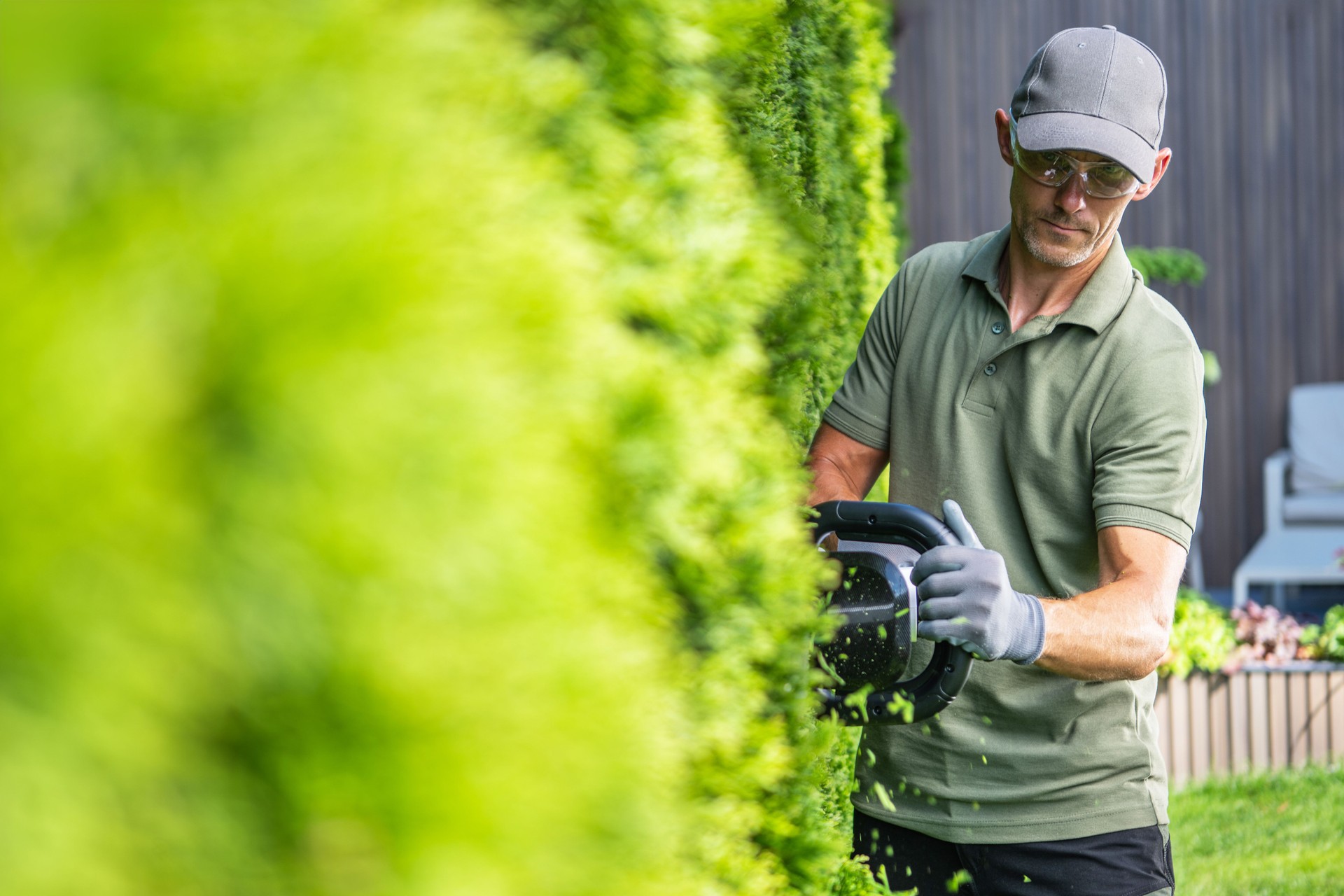 Man Trimming a Green Hedge in a Backyard on a Sunny Day